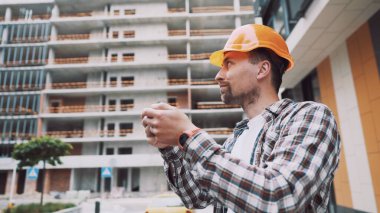 İnşaat alanında akıllı telefonla çalışan bir mimar. Mühendis, akıllı telefondan inşaat planını kontrol et. İnşaat müfettişi, akıllı telefon ekranındaki tesislerdeki inşaat projesini doğruladı.