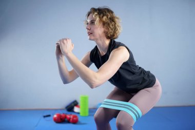 Spor giyim kuşağında çıplak ayaklı atletik bir kadın esnek kumaş egzersiz bantlarını spor salonu için bant, ağırlık kaldırma, antrenman kasları için kullanıyor. Sıska kız iyi durumda..