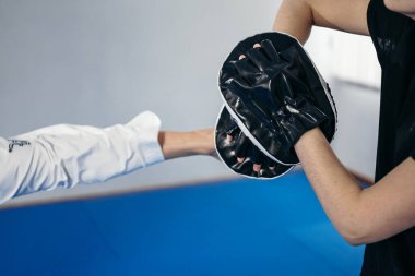 Tekvandonun kişisel dövüş sanatı. Tekvando tekmeleme pedi tutan kadın antrenör, spor ayakkabısı tekmeleri. Kadın vuruş kalkanını tekmeliyor, koçla antrenman yapıyor. Dövüşçüler birlikte çalışır..