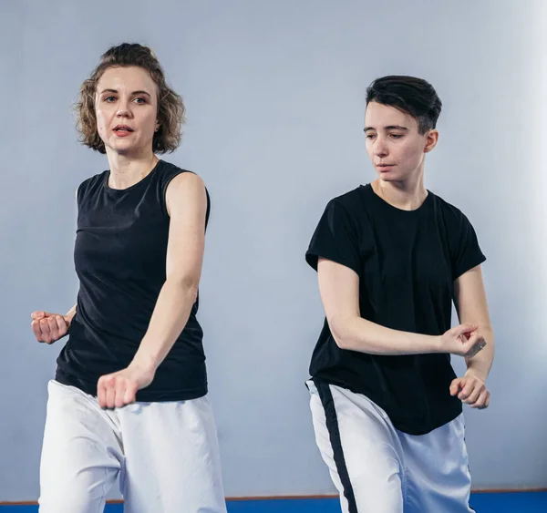 Two female fighter of martial arts practice in gym. Taekwondo coach and student in personal training. Self-defense class for women. Fighters training together. Karateka training with master.