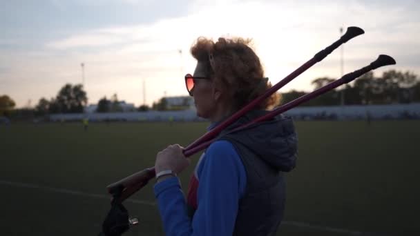 Seniorin trainiert mit Gehstöcken im Stadion Reife Frauen machen Nordic-Walking-Übungen auf der Laufstrecke. Gesunder Lebensstil. Aktives Frauentraining mit Trekkingstöcken in der Stadt