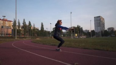 Son sınıf atletik bayan, İskandinav yürüyüşü antrenmanından önce koşu stadyumunda sopayla fiziksel egzersiz yapıyor. Yaşlılıkta sportif yaşam tarzları. Yaşlı kadın dışarıda sırıklarla antrenman yapıyor.