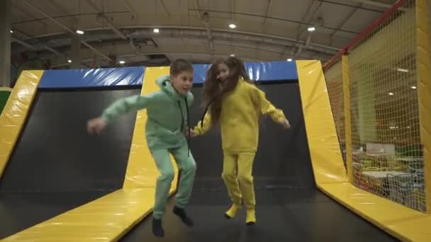 Lazer ativo. Crianças se divertindo no trampolim no centro de entretenimento, infância e estilo de vida esportivo. Menino e menina no centro de lazer spotr para crianças. Irmão e irmã se entregam a trampolins — Vídeo de Stock