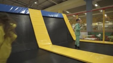 Çocuk oyun merkezinde zaman geçirirken şirin ikiz kardeşler trambolinde zıplıyor ve zıplıyorlar. Spor ve eğlence konsepti. Çocuk sporları ve hobileri