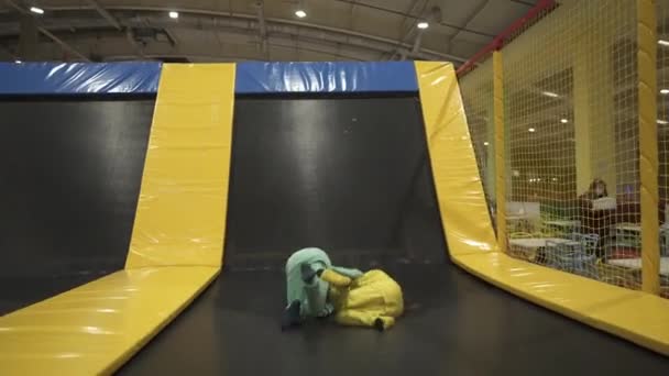 Happy smiling 11 years old kids jumping on trampoline indoors in entertainment center. Active children leisure, jumping and playing on trampoline in sport center. Amusement park. Sport activity — Stock Video