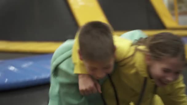 Carino fratello gemello e sorella che saltano e rimbalzano insieme sul trampolino coperto quando trascorrono del tempo nel centro giochi per bambini. Concetto di sport e intrattenimento. Sport e hobby per bambini — Video Stock