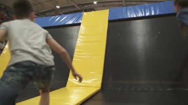 Aktif boş zaman. Çocuklar trambolinde eğleniyor eğlence merkezinde, çocuklukta ve sportif yaşam tarzında. Çocuklar için eğlence merkezindeki kız ve erkek. Erkek ve kız kardeş trambolinlere dalar.