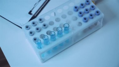 Koruyucu tulum giyen bilim adamı ya da doktor mavi reaktörlü test tüpü, kimyasal sıvı, mikroskop, laboratuvar biyokimyası içeren laboratuvar camları alıyor. Tıp ve araştırma konsepti