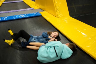 Aktif boş zaman. Çocuklar trambolinde eğleniyor eğlence merkezinde, çocuklukta ve sportif yaşam tarzında. Çocuklar için eğlence merkezindeki kız ve erkek. Erkek ve kız kardeş trambolinlere dalar..