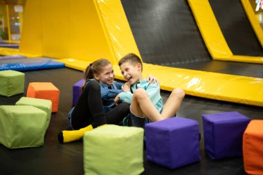 Eğlence merkezinde trambolinde zıplayan 11 yaşındaki mutlu çocuklar. Aktif çocuk eğlencesi, spor merkezinde trambolinde zıplamak ve oynamak. Eğlence parkı. Spor etkinliği.