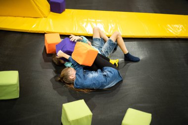 Aktif boş zaman. Çocuklar trambolinde eğleniyor eğlence merkezinde, çocuklukta ve sportif yaşam tarzında. Çocuklar için eğlence merkezindeki kız ve erkek. Erkek ve kız kardeş trambolinlere dalar..