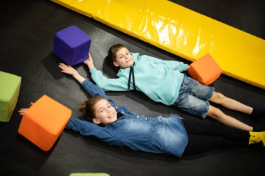 Çocuk oyun merkezinde zaman geçirirken şirin ikiz kardeşler trambolinde zıplıyor ve zıplıyorlar. Spor ve eğlence konsepti. Çocuk sporları ve hobileri.