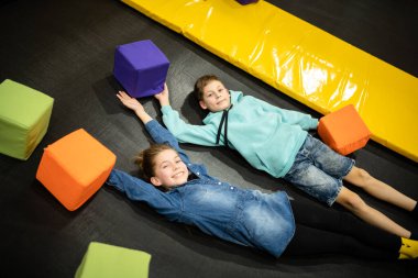 Aktif boş zaman. Çocuklar trambolinde eğleniyor eğlence merkezinde, çocuklukta ve sportif yaşam tarzında. Çocuklar için eğlence merkezindeki kız ve erkek. Erkek ve kız kardeş trambolinlere dalar..