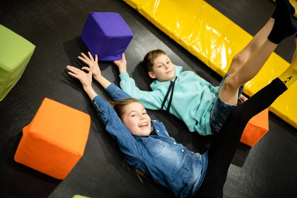 Çocuk oyun merkezinde zaman geçirirken şirin ikiz kardeşler trambolinde zıplıyor ve zıplıyorlar. Spor ve eğlence konsepti. Çocuk sporları ve hobileri.