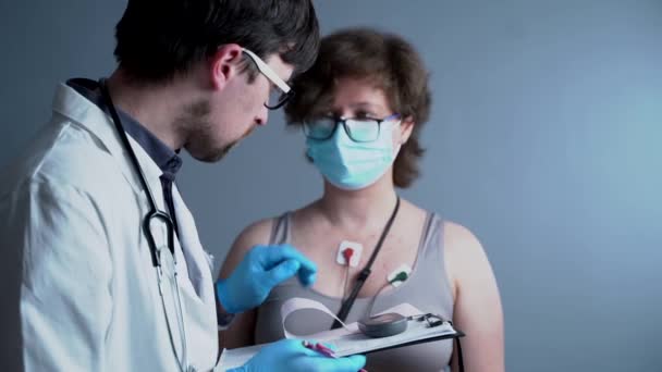 심장병 치료. 건강 관리. 정신과 의사의 심장 질환 진단젊은 여성 환자는 휴대가 가능 한 심전도, 홀 터 모니터 검사를 이용 한다. ECG 전자기류 — 비디오