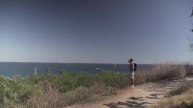 Yürüyüşçü Lycian yolunda. Yazın güneşli bir havada sırt çantasıyla deniz kenarında ve dağlarda yürüyüş yapan bir adam. Sırt çantalı erkek gezgin mavi deniz suyunun tadını çıkartıyor. Sahilde yürüyüş.