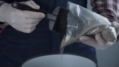 Üniformalı erkek bahçıvanın elleri ve eldiven nakledilen kozalaklı kozalaklı her zaman yeşil ağaçtan ev bitkisini gri arka planda yeni bir çömleğe yerleştirir. Küçük ladin ağacını büyük tencerede yeniliyorum.