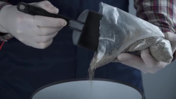 Handen close-up van mannelijke tuinman in uniform en handschoenen transplanteert huis plant van geslacht van naaldbomen groenblijvende bomen in nieuwe pot op grijze achtergrond binnen. Herplanten van kleine sparren boom in grote pot — Stockvideo