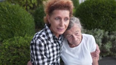 Aile bağları. Anneler ya da Uluslararası Kadınlar Günü. Mutlu anne ve yetişkin kız kucaklaşmaları, evin yakınındaki şehir parkında bankta oturmanın tadını çıkarmaları. Aile, nesil, insan kavramı