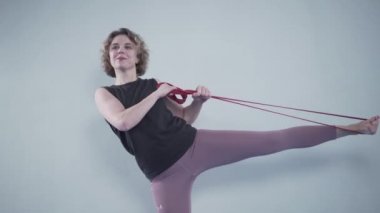 Sporcu kadın direniş bandıyla egzersiz yapıyor. Millet, spor ve spor. Spor salonunda spor grubuyla antrenman yapan genç bir kadın. Aktif yaşam tarzı. Lastik bant ile antrenman. Lastik genişletici