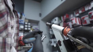 Çevre dostu elektrikli araç tamir servisi. Beyaz erkek elektrikli taşıma tamircisi istasyonda çalışıyor. Tamir ve hizmet için atölyede çalışan adam, elektrik itme scooterını tamir ediyor.