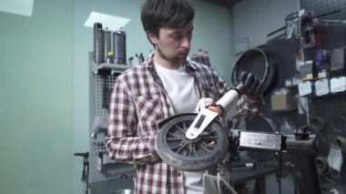 Atölyede elektrikli scooter üzerinde çalışan profesyonel bir zanaatkar. Çocukların tekerleklerini tamir eden teknisyenler tamir atölyesinde scooter satıyorlar. Tamirci işte. Çevre dostu nakliye aracı. Scooter bakım servisi