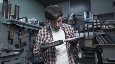 Kafkas erkek tamirci tamircide çalışıyor, çocukları tamir ediyor, scooterı tekmeliyor. Scooter tamir, bakım servisi. Ekolojik nakliye. Özel atölyedeki elektrikli scooter tamiri