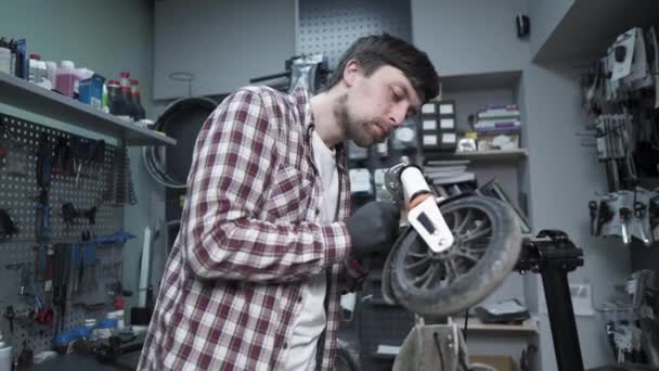 Jeune mécanicien masculin caucasien travaillant dans un atelier de réparation, réparer les enfants coup de pied scooter. Scooter de réparation, service d'entretien. Transport écologique. Réparation scooter électrique dans un atelier spécial — Video