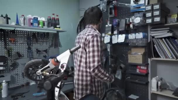 Homme ingénieur mécanique, réparateur répare les dommages mécaniques à la roue de scooter enfants. Petite entreprise pour le service et l'entretien du transport écologique des scooters. Broken kick e scooter — Video