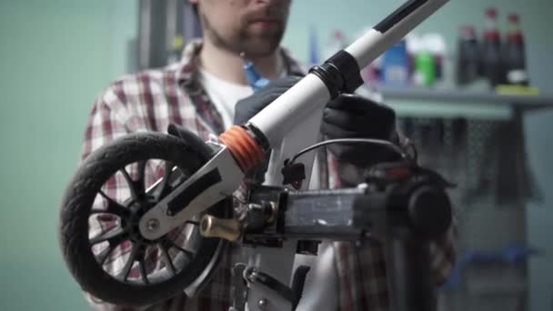 Erkek makine mühendisi, tamirci çocuk scooterındaki mekanik hasarı tamir ediyor. Mobiletlerin ekolojik taşımacılığında hizmet ve bakım için küçük bir işletme. Kırık tekme e scooter — Stok video