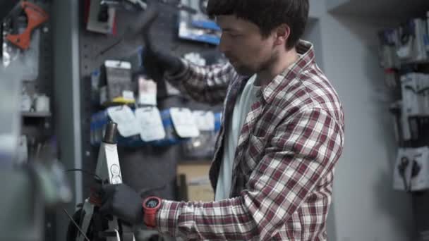 Reparationsverkstad för elmopeder. Mekaniker håller i sin hand brutna del av barn skoter och hjul. Moderna miljövänliga transportsätt. Reparatörarbetare under arbete i verkstad — Stockvideo