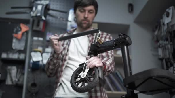 Artesano profesional trabajando en scooter eléctrico en taller. Los técnicos que fijan la rueda de los niños empujan el scooter en el taller de reparación. Mecánico trabajando. Transporte ecológico. Servicio de mantenimiento de vespa — Vídeo de stock