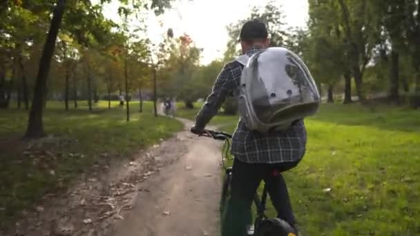 Muž cyklista cestuje s kočkou v průhledném batohu na horském kole. Přátelství se zvířaty, láska ke zvířatům. Pořád spolu. Happy pedaling muž cyklista s domácí kočkou v nosič na zadní straně — Stock video
