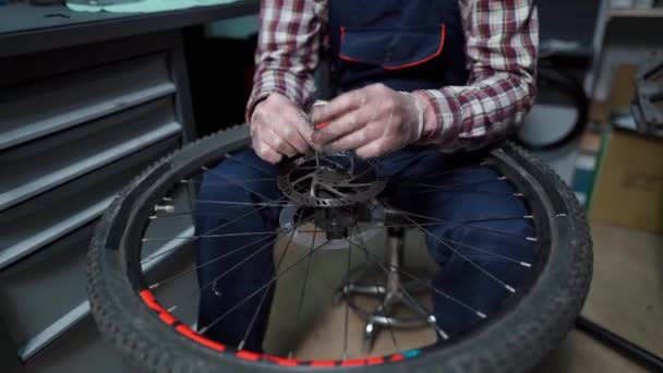 Jonge Kaukasische reparateur repareert mountainbike wiel in fietsenwinkel werkplaats. Fietsenmaker. Zorgen voor jullie wielen. Een monteur die in de garage werkt. Werknemer reparatie cyclus vistuig. Thema voor kleine bedrijven — Stockvideo