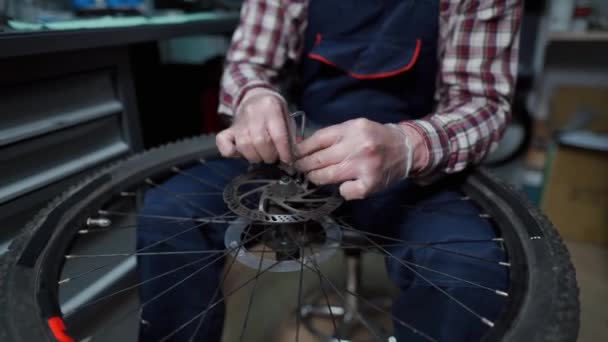 Fietsenmaker monteur bevestiging fietswiel in werkplaats. Serviceman reparatie, onderhoud cyclus. Velocipede reparatie fiets in de fietsenwinkel. Fietsreparatie concept. Milieuvriendelijke voertuigen — Stockvideo