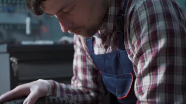 Bisiklet tamirhanesinde teknik uzmanlık. Atölyede bisiklet tekerleğini tamir eden yakışıklı genç bir tamirci. Dağ bisikletine servis yapan iş elbisesi tamircisi. Erkek mühendis hızını ayarlıyor.