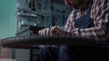 Tamirhanede bisiklet tamircisi bisiklet tekerleğini tamir ediyor. Velocipede servisi. Tamirci erkek bisikletçi atölyede bisiklet tekerleğini tamir ediyor. Teknisyen bisiklet parçalarını tamir ediyor. İş yerindeki tamirci.