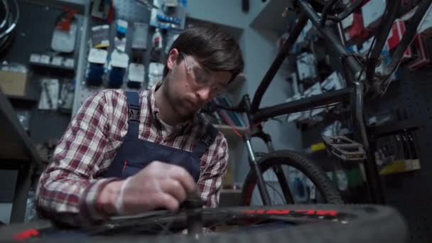 Механик веломастерской фиксирует велосипедное колесо в мастерской. Ремонт, техническое обслуживание. Велоципед ремонтирует велосипед в байк-шопе. Концепция ремонта велосипедов. Экологически чистые автомобили — стоковое видео