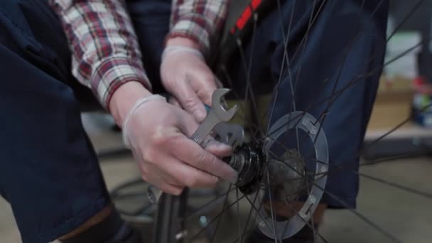Tamirhanede bisiklet tamircisi bisiklet tekerleğini tamir ediyor. Velocipede servisi. Tamirci erkek bisikletçi atölyede bisiklet tekerleğini tamir ediyor. Teknisyen bisiklet parçalarını tamir ediyor. İş yerindeki tamirci. — Stok video