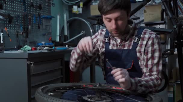 Roue de cycle de fixation de mécanicien de vélo dans l'atelier de réparation. Service Velocipede. Repairer homme atelier de vélo ingénieur fixer roue de vélo dans l'atelier. Technicien fixe les pièces de vélo. Homme à tout faire au travail sur le lieu de travail — Video