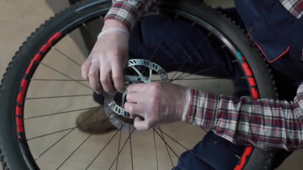 Mécanicien masculin travaillant dans un atelier de réparation de vélos, mécanicien réparant le vélo à l'aide d'un outil spécial, portant des gants de protection. Jeune militaire attrayant fixant clients roue de vélo à son propre atelier — Video