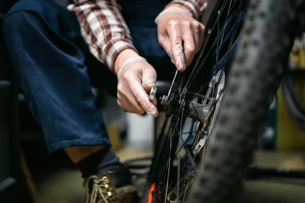 Bike shop mechanic fixing bicycle wheel in workshop. Serviceman repair, maintenance cycle. Velocipede repairing bicycle in bike shop. Bicycle repair service concept. Environmentally friendly vehicles.