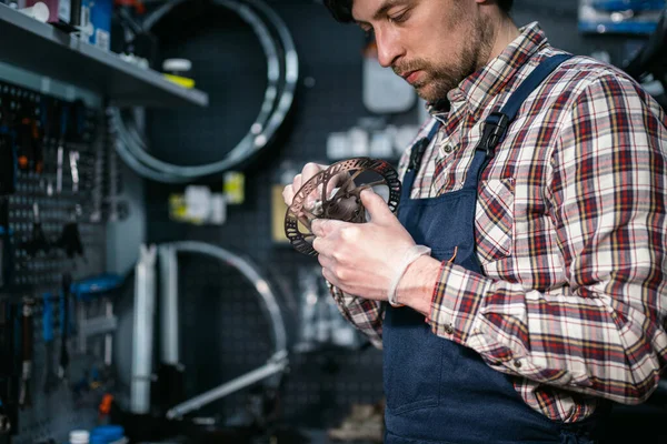 Bike shop mechanic fixing bicycle wheel in workshop. Serviceman repair, maintenance cycle. Velocipede repairing bicycle in bike shop. Bicycle repair service concept. Environmentally friendly vehicles.