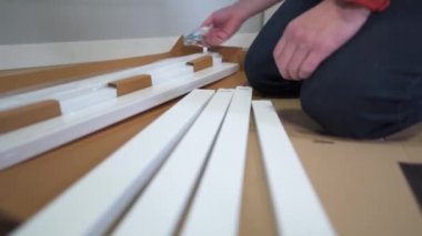 DIY beyaz masa montaj işlemi evde yapılıyor. Mobilya döşemesi. Yeni ev ve mobilya montajı yapan adam bunu kendi başına yapıyor. Kattaki talimatlara göre, kutudan itibaren erkek montaj tablosu