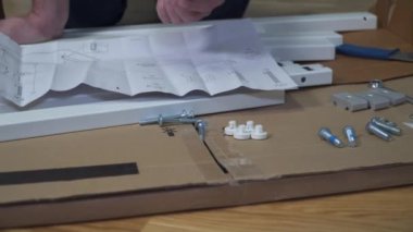 Adam evde mobilya montajı yapıyor. Adam internetten mobilya almış, karantina sırasında talimatlara göre masayı kendisi monte etmiş. Eve mobilya sipariş et