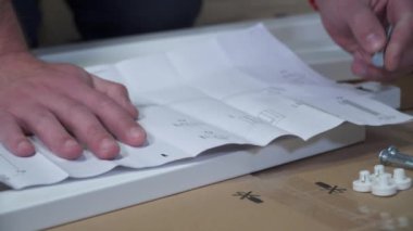Adam evde mobilya montajı yapıyor. Adam internetten mobilya almış, karantina sırasında talimatlara göre masayı kendisi monte etmiş. Eve mobilya sipariş et