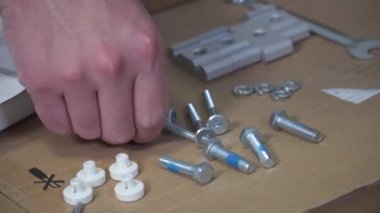 Genç beyaz adam talimatları kullanarak beyaz mobilyaları düz kutudan topluyor. Erkek, karantina sırasında online DIY almış. Coronavirus 'u kilitleyin. Mobilyaları ev ve kendi kendine monte edin.