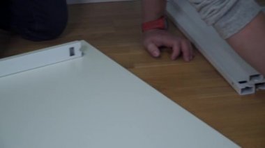 Yeni eve taşınıyorum. Kutuları açmak ve mobilyaları monte etmek. Adam talimatları okuyor ve mobilyaları monte ediyor. DIY. Erkek, yeni beyaz mobilyalar kuruyor. Kendiniz yapın. Mobilya montaj süreci
