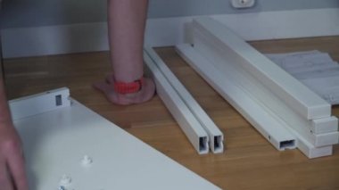 DIY beyaz masa montaj işlemi evde yapılıyor. Mobilya döşemesi. Yeni ev ve mobilya montajı yapan adam bunu kendi başına yapıyor. Kattaki talimatlara göre, kutudan itibaren erkek montaj tablosu