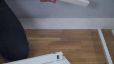 Genç beyaz adam talimatları kullanarak beyaz mobilyaları düz kutudan topluyor. Erkek, karantina sırasında online DIY almış. Coronavirus 'u kilitleyin. Mobilyaları ev ve kendi kendine monte edin.